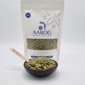 A pack of Aarog organic pumpkin seeds next to a bowl of fresh seeds
